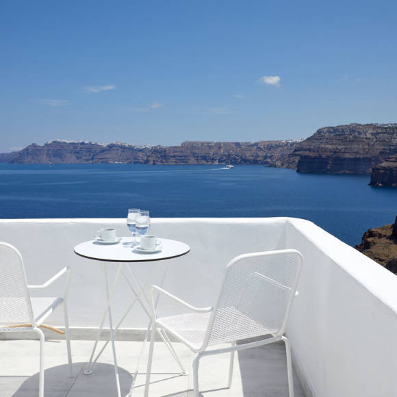 Santorini View Hotel balcony with caldera view, white table seats, greek coffee and glasses of water