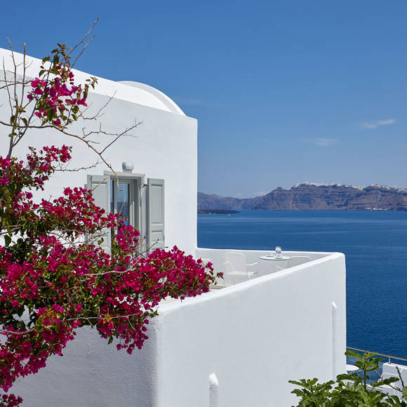 Santorini View Hotel room with caldera sea view and white balcony with fuchsia bougainvillea undeer the blue sky