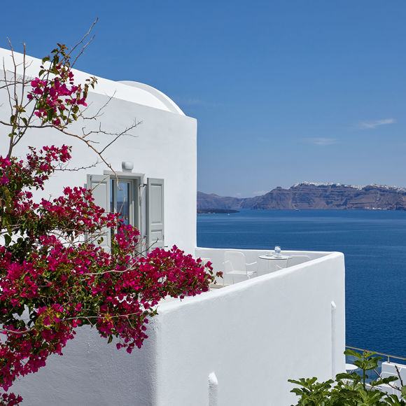 Santorini View Hotel room with caldera sea view and white balcony with fuchsia bougainvillea undeer the blue sky