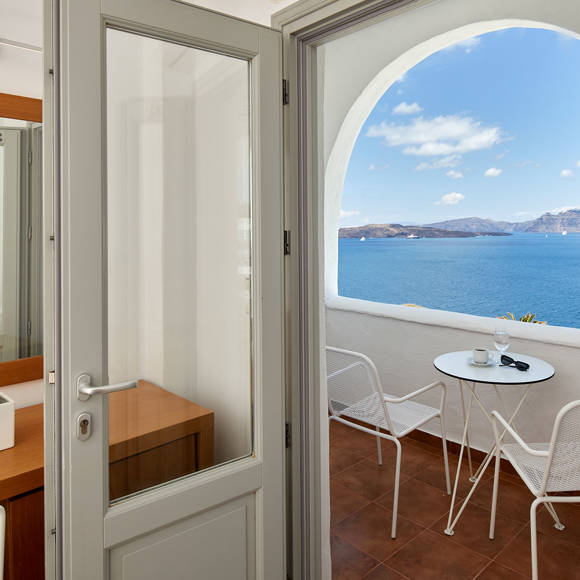 Santorini View Hotel room with white door to sea view balcony with table and chairs