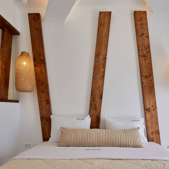 Santorini View Hotel double bed with white and beige linen, and bamboo ceiling lamps